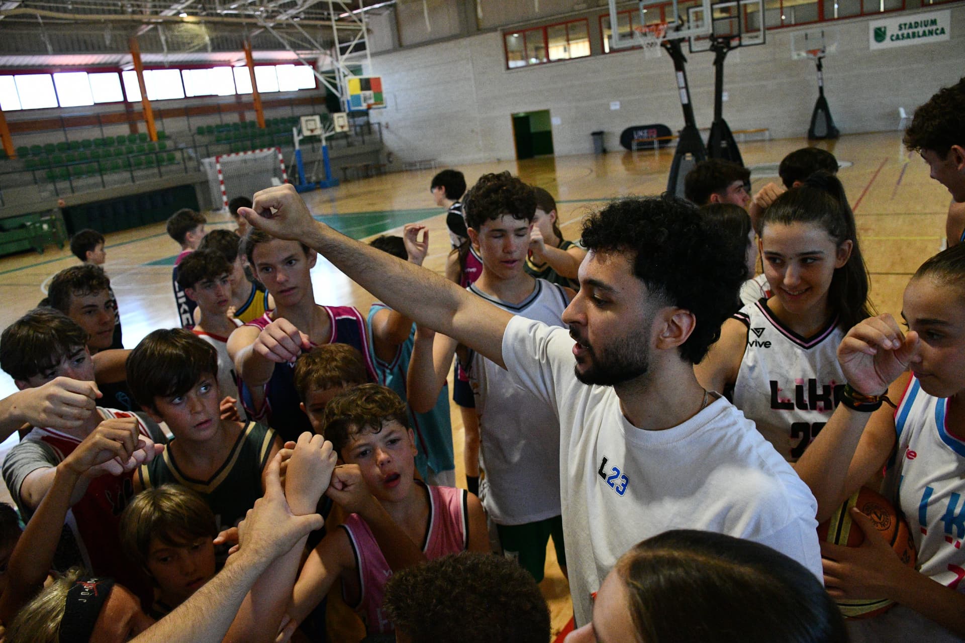 Seif Amer coaching a basketball team huddle
